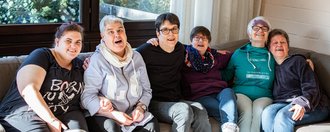 Gruppe von Menschen mit Behinderung lachen und sitzen auf einer Couch