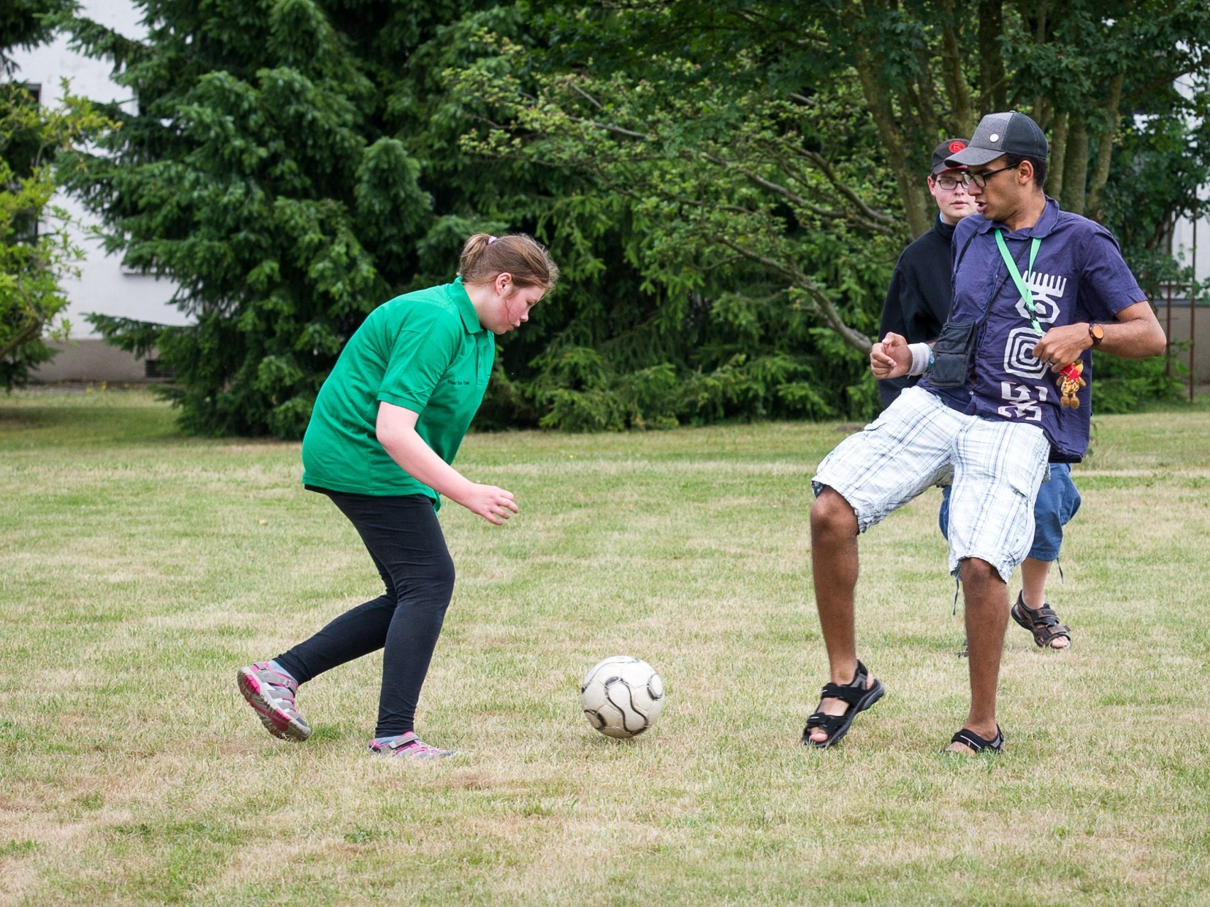 Sport: Ein junges Mädchen und zwei Jungen spielen Fußball