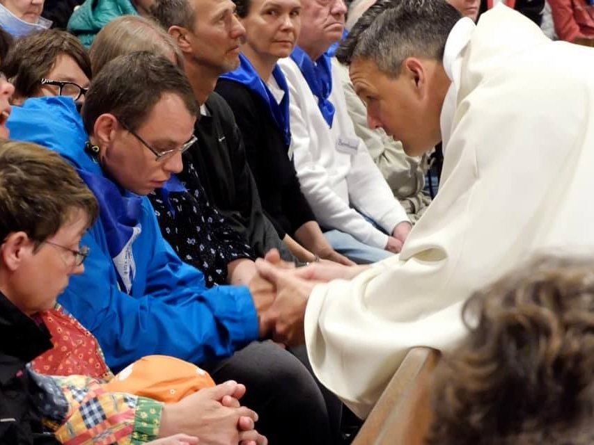 In der Kirche: Gottesdienst mit vielen Besuchern - Pater Jörg hält die Hand eines jungen Mannes