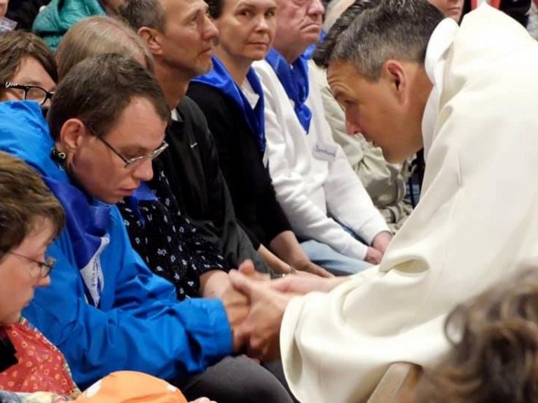 In der Kirche: Gottesdienst mit vielen Besuchern - Pater Jörg hält die Hand eines jungen Mannes