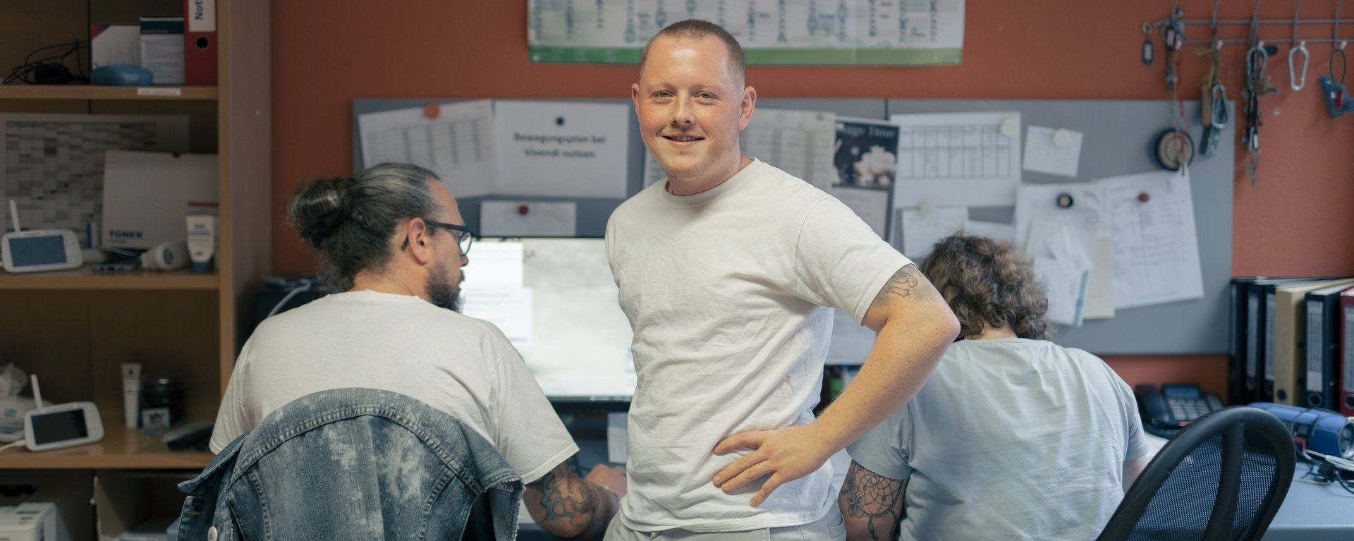 Mitarbeiter Arbeiten am Computer und ein Mann lacht in die Kamera 