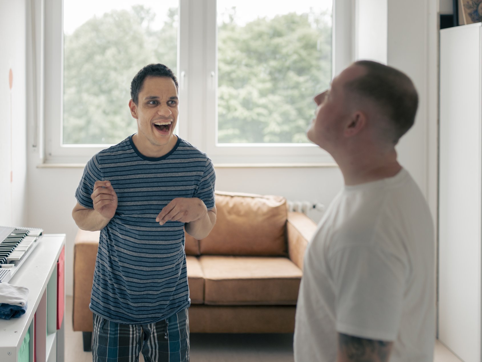 En Pflefer und ein Bewohner stehen zusammen im einem Zimmer und lachen zusammen 