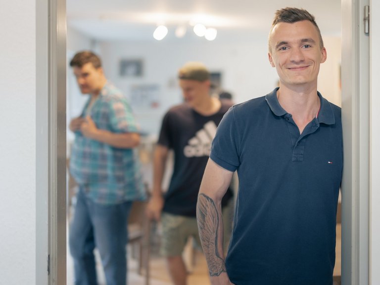 Mitarbeiter des Haus Nettetal steht mit Bewohnern im Türrahmen 