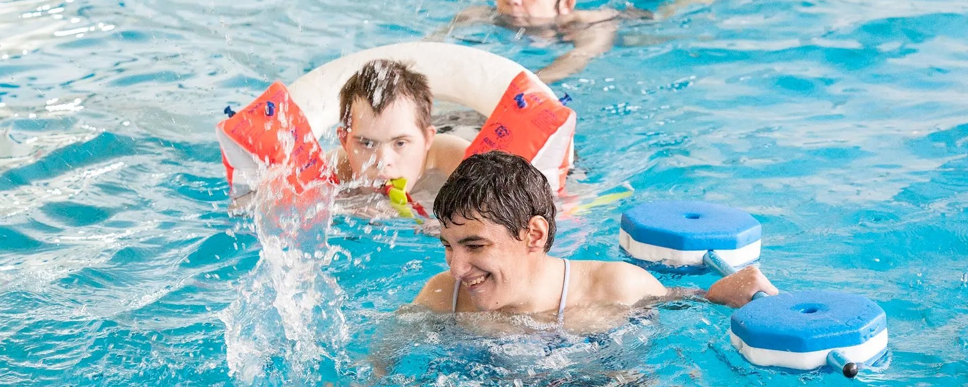 im Schwimmbad: Mädchen und Jungen mit Schwimmhilfen im Schwimmbecken