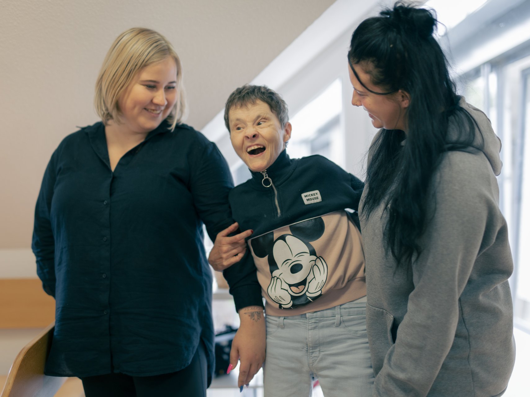 Zwei Mitarbeiterinnen des Hauses Nettetal lachen zusammen mit einer behinderten Bewohnerin