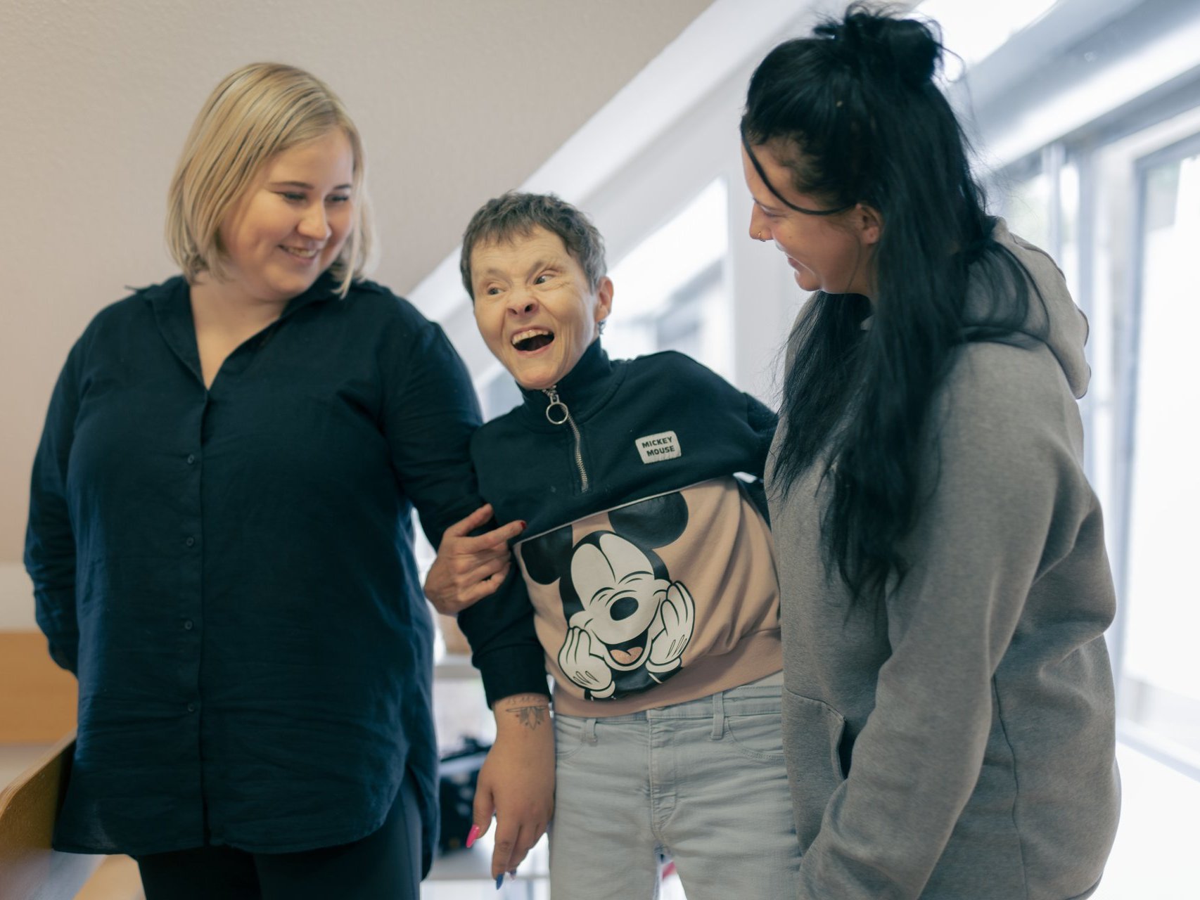 Zwei Mitarbeiterinnen des Hauses Nettetal lachen zusammen mit einer behinderten Bewohnerin